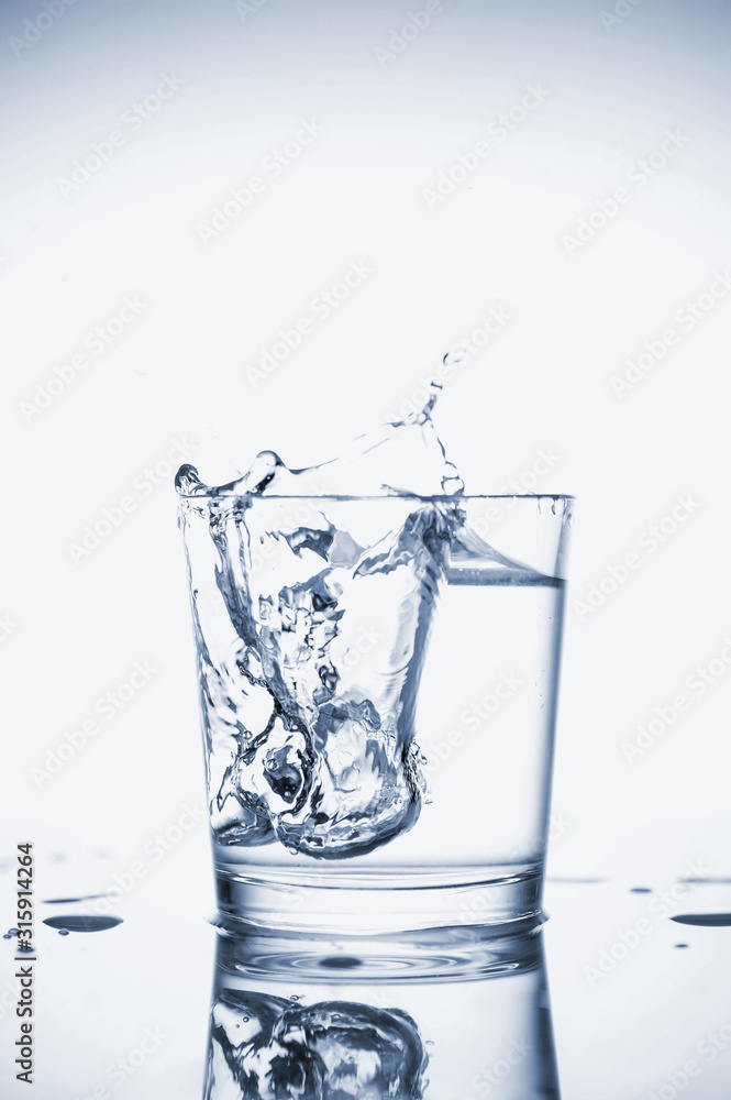 Clear mineral water splashes in a glass with ice. Clear mineral water splashes in a glass with ice.