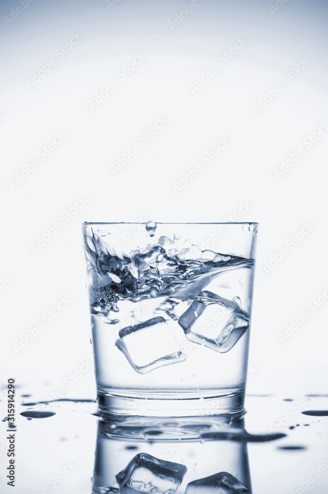 Clear mineral water splashes in a glass with ice. Clear mineral water splashes in a glass with ice.
