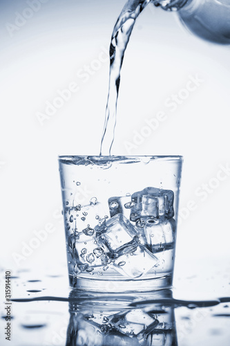 Clear mineral water is poured into a glass with ice.