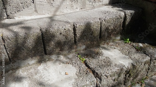 Steps from old building blocks. Expanded clay blocks are slightly covered with moss and plants. Illuminated by the sun, there are shadows.