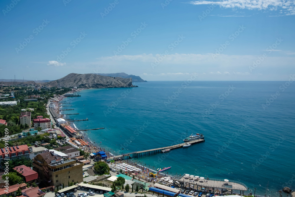 Sunny summer day. View of city from above. Black sea and mountains. Sudak, Crimea.