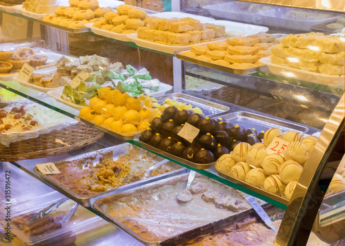 A variety of delicious Indian Bengali Sweets - gulab jamun, rasogulla, kaju barfi, kheer kadam, sandesh and laddu displayed on the street side food stall in Kolkata for sale.