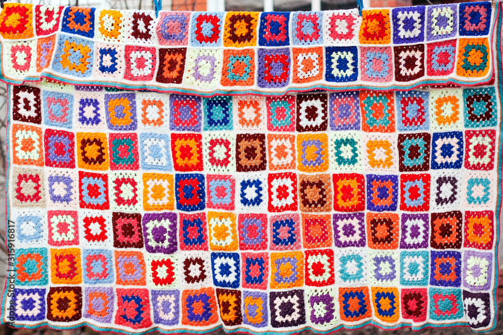 Colorfull handmade crochet blanket afgan made from woolen granny squares hanging outdoors Colorfull handmade crochet blanket afgan made from woolen granny squares hanging outdoors