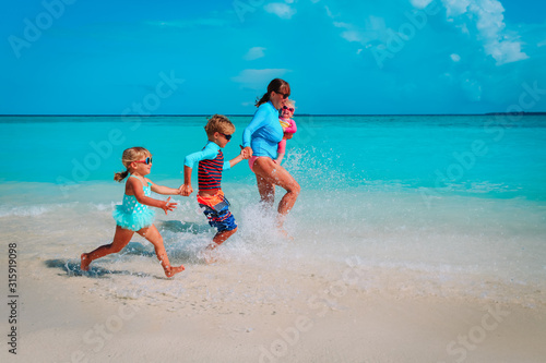 mother with kids play with water run on beach