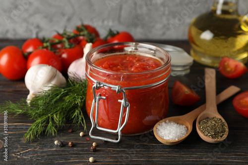 Chilli sauce, garlic, cherry tomatoes, olive oil, spices on wooden background, space for text. Closeup