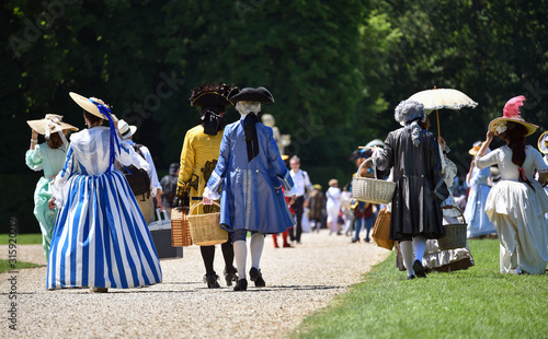 Unidentified people costumed in the fashions of the 17th french aristocracy, walking in French formal gardens.
