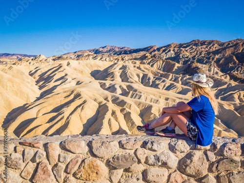 Sexy curvy woman admires the Landscape from the top of Zabriskie Point in Death Valley National Park in California. It is one of the hottest places in the world.