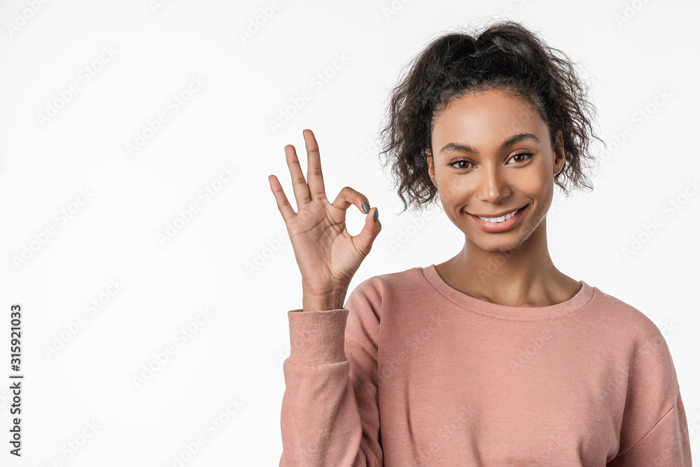American woman smiling on camera and gesturing ok sign isolated over white background American woman smiling on camera and gesturing ok sign isolated over white background