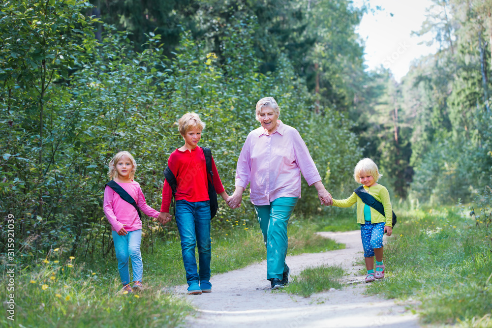 Obraz premium happy senior grandmother with kids walk in nature