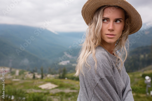 Joyful young attractive girl rejoices in conquering peaks and while climbing mountains during holidays. Pretty girl travel blogger has discovered new places. Achievement goals and success concept