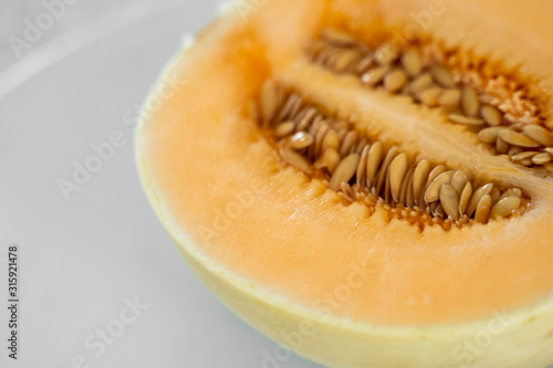 Fresh sweet orange melon on the white plate as a background with a selective focusing. Useful and vitamin-rich food. Vegeterian.