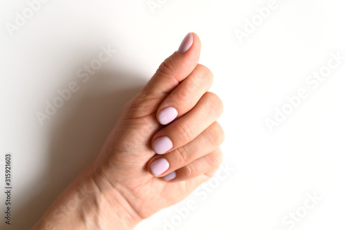 woman's hand with pale lilac painted nails on a white background