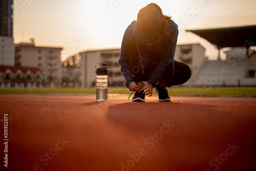 Beautiful female athletes tie shoelaces on sneakers. Beautiful female athletes are sitting on a shoelace on a black sneakers. Healthy lifestyle concepts