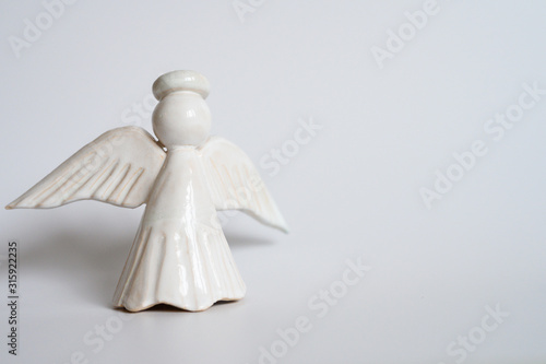 white ceramic craft angel with wings and halo on a white background. space for text