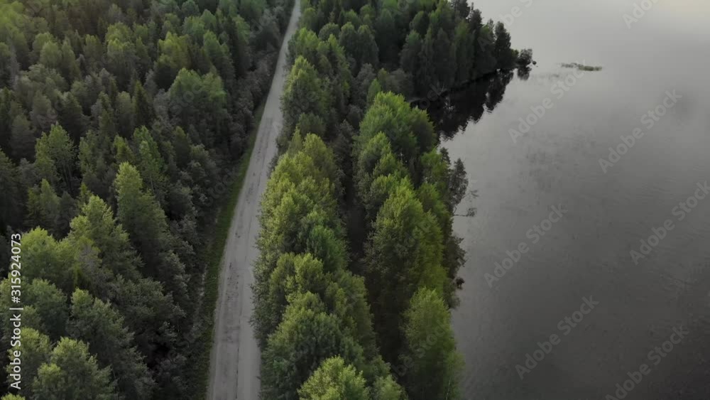 Beautiful panorama over the tops of the green, old forest in the midst of which is located the highway. The trees are reflected in a large lake. Landscape of untouched nature. The picture was taken by Beautiful panorama over the tops of the green, old forest in the midst of which is located the highway. The trees are reflected in a large lake. Landscape of untouched nature. The picture was taken by