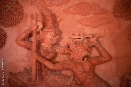 Hanuman monkey god fighting Thotsakan giant stucco tracery sculpture public place in thialnd temple, Based on the character in Ramakien or Ramayana Literature photo