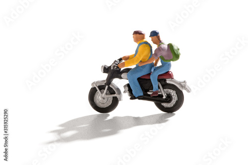 Two miniature men on motorbike on white