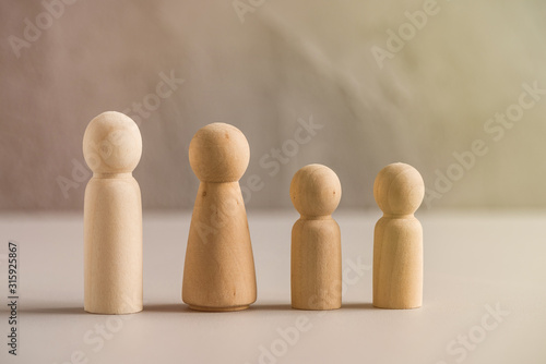 Wooden people man, woman and children against the background of a gray concrete wall. The concept and symbol of the large family. Family Care Concept