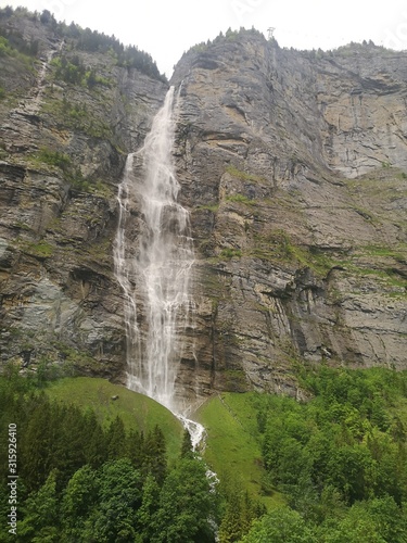 Tall and beautiful waterfall at a huge rock face in Switzerland