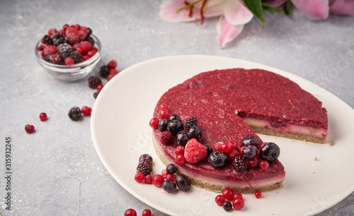 Raw vegan berry cherry cheesecake gluten-free on grey background.