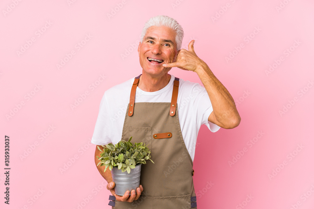 Middle aged gardener man isolated showing a mobile phone call gesture with fingers. Middle aged gardener man isolated showing a mobile phone call gesture with fingers.