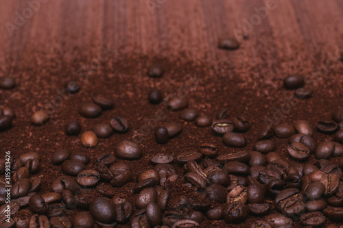 Coffee beans and ground coffee are scattered on a brown wooden background. Good morning to everyone who is in love with coffee.
