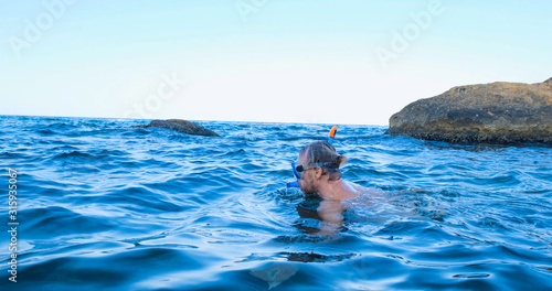 Young male swimmer with snorkling glasses dive in the summer sea	
