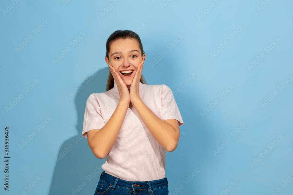 Astonished, wondered. Caucasian teen girl's portrait on blue background. Beautiful model in casual wear. Concept of human emotions, facial expression, sales, ad. Copyspace. Looks cute, happy. Astonished, wondered. Caucasian teen girl's portrait on blue background. Beautiful model in casual wear. Concept of human emotions, facial expression, sales, ad. Copyspace. Looks cute, happy.