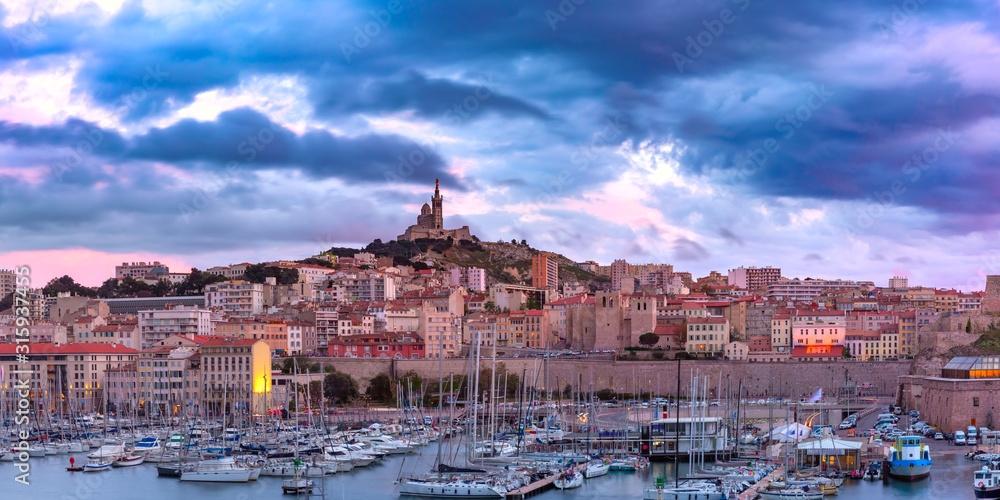Panoramic view of Old Port and the Basilica of Notre Dame de la Garde on the background on the hill at sunset, Marseille, France
