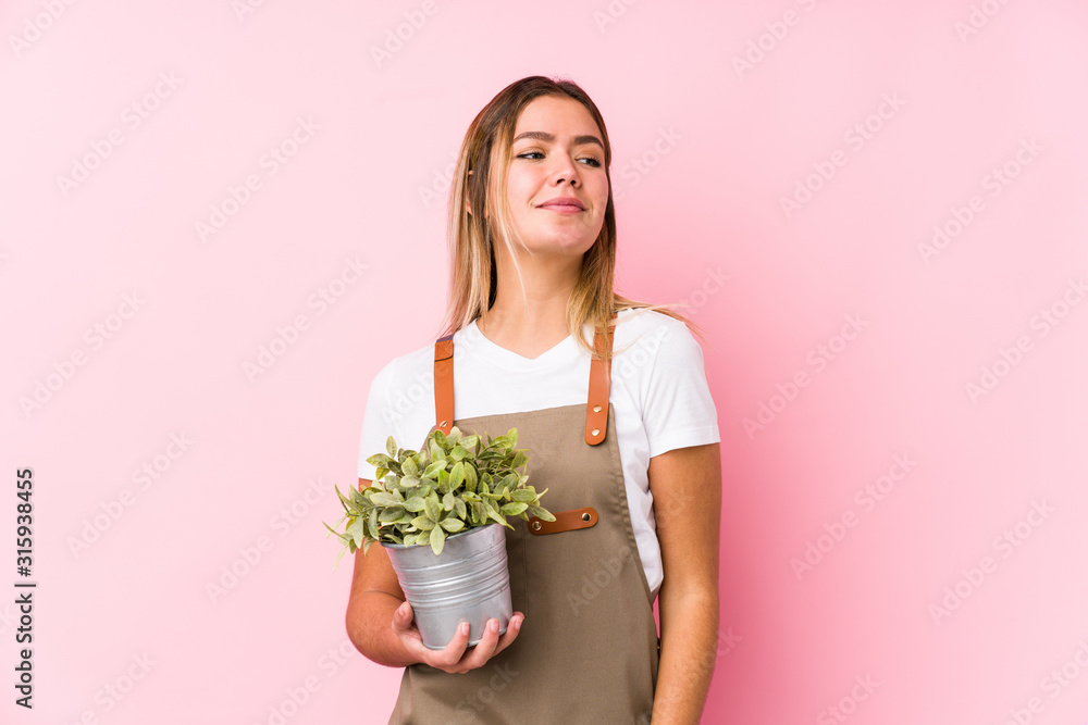 Young caucasian gardener woman in a pink background dreaming of achieving goals and purposes Young caucasian gardener woman in a pink background dreaming of achieving goals and purposes