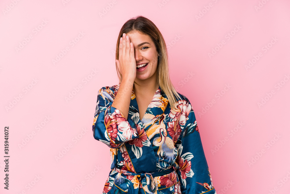 Young caucasian woman wearing pajamas having fun covering half of face with palm. Young caucasian woman wearing pajamas having fun covering half of face with palm.