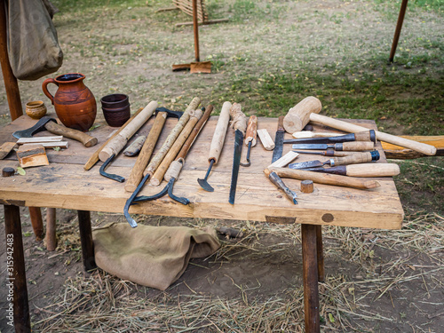 Old woodworking hand tool: wooden plane, chisel ax, sledgehammer, hammer and in a carpentry workshop on dirty rustic table covered with sawdust background side view photo