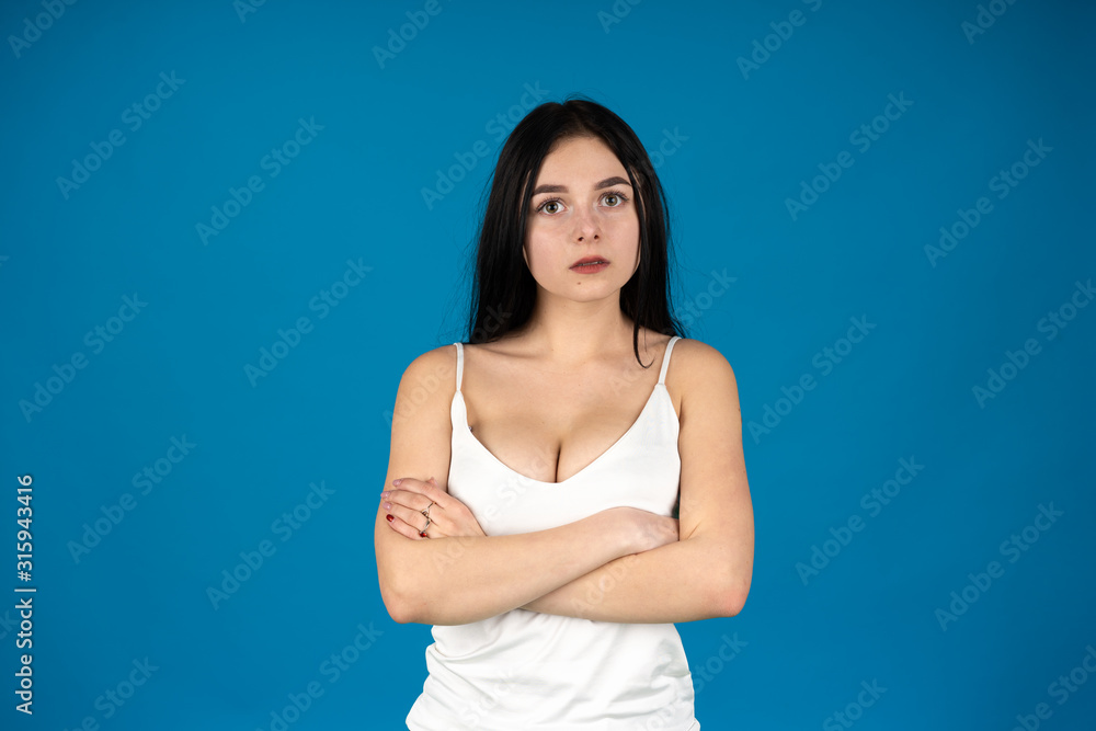 Front view of attractive woman posing with folded arms isolated on blue background Front view of attractive woman posing with folded arms isolated on blue background