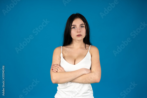 Front view of attractive woman posing with folded arms isolated on blue background
