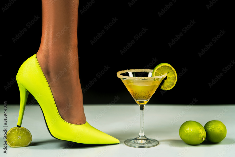 Cocktail party. Neon colorful cocktail in glass. Sexy legs in neon high  heels crush lime. Party club entertainment. Summer cocktail party. Tropical  beverage to enjoy celebration of warm season. Photos
