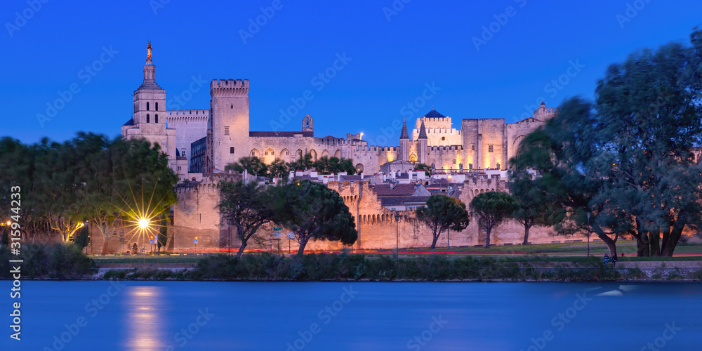 Panoramic view of famous medieval Saint Benezet bridge and Palace of the Popes during evening blue hour, Avignon, southern France