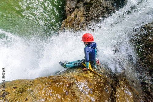 Mutprobe beim Canyoning - Felsrutsche in einen Wasserfall photo