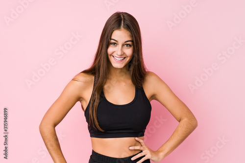Young caucasian fitness woman doing sport isolated confident keeping hands on hips.
