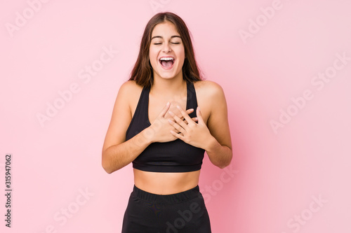 Young caucasian fitness woman doing sport isolated laughing keeping hands on heart  concept of happiness.