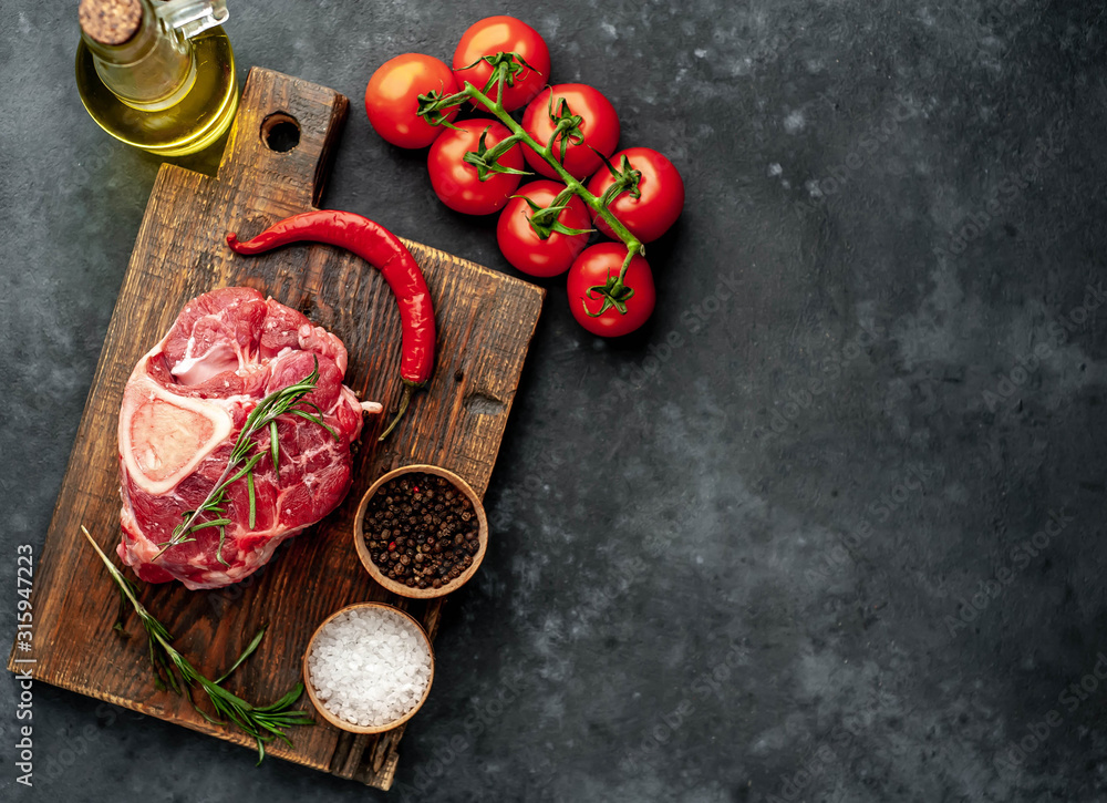 Raw beef steak with tomatoes and spices on a concrete background with copy space for your text. Raw beef steak with tomatoes and spices on a concrete background with copy space for your text.