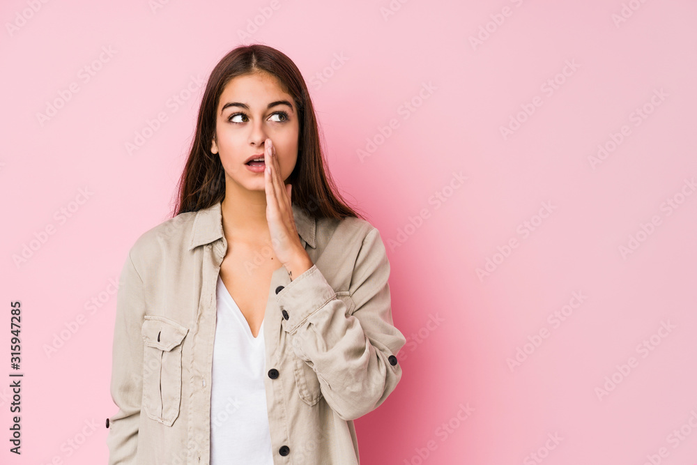 Young caucasian woman posing in a pink background is saying a secret hot braking news and looking aside Young caucasian woman posing in a pink background is saying a secret hot braking news and looking aside
