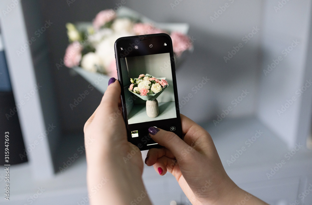 girl blogger takes a photo of flowers on her phone