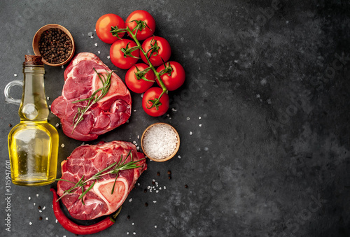 two raw beef steaks with tomatoes and spices on a concrete background with copy space for your text. Concept of cooking dinner for two