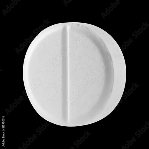 White round pill on a black isolated background. Big pill close up.
