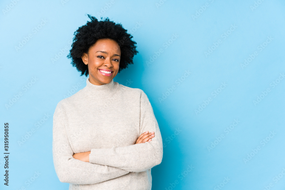 Middle aged african american woman against a blue background isolated smiling confident with crossed arms. Middle aged african american woman against a blue background isolated smiling confident with crossed arms.