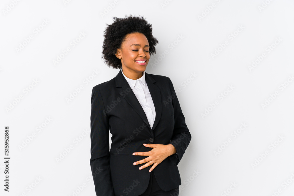 Middle aged african american business woman against a white background isolated touches tummy, smiles gently, eating and satisfaction concept. Middle aged african american business woman against a white background isolated touches tummy, smiles gently, eating and satisfaction concept.