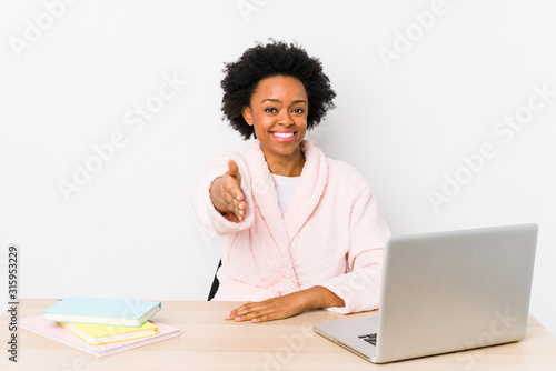 Middle aged african american woman working at home isolated stretching hand at camera in greeting gesture.