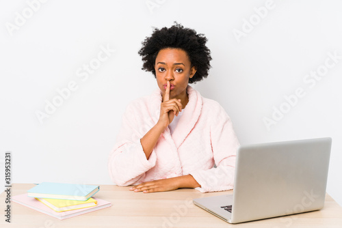 Middle aged african american woman working at home isolated keeping a secret or asking for silence.