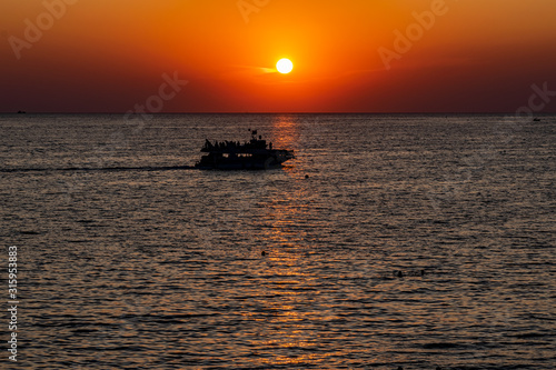 Красивый, красочный и контрастный закат над морем, океаном. Горячее солнце освещает просторный пейзаж, отбрасывая блики лучей на водную гладь. Яркий солнечный восход. Путешествие и туризм. © Анна Иванова