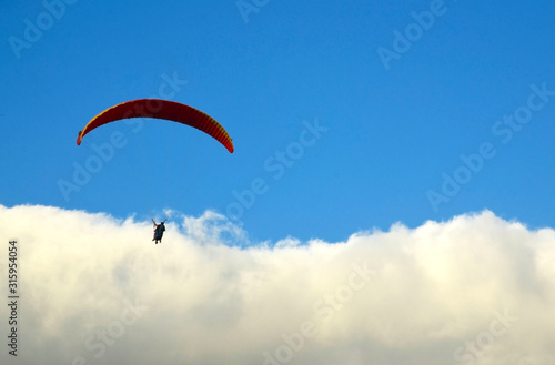 Paraglider flying against blue sky with clouds in south Tenerife,Canary Islands,Spain.Paragliding.Concept of extreme sport activity.Selective focus.